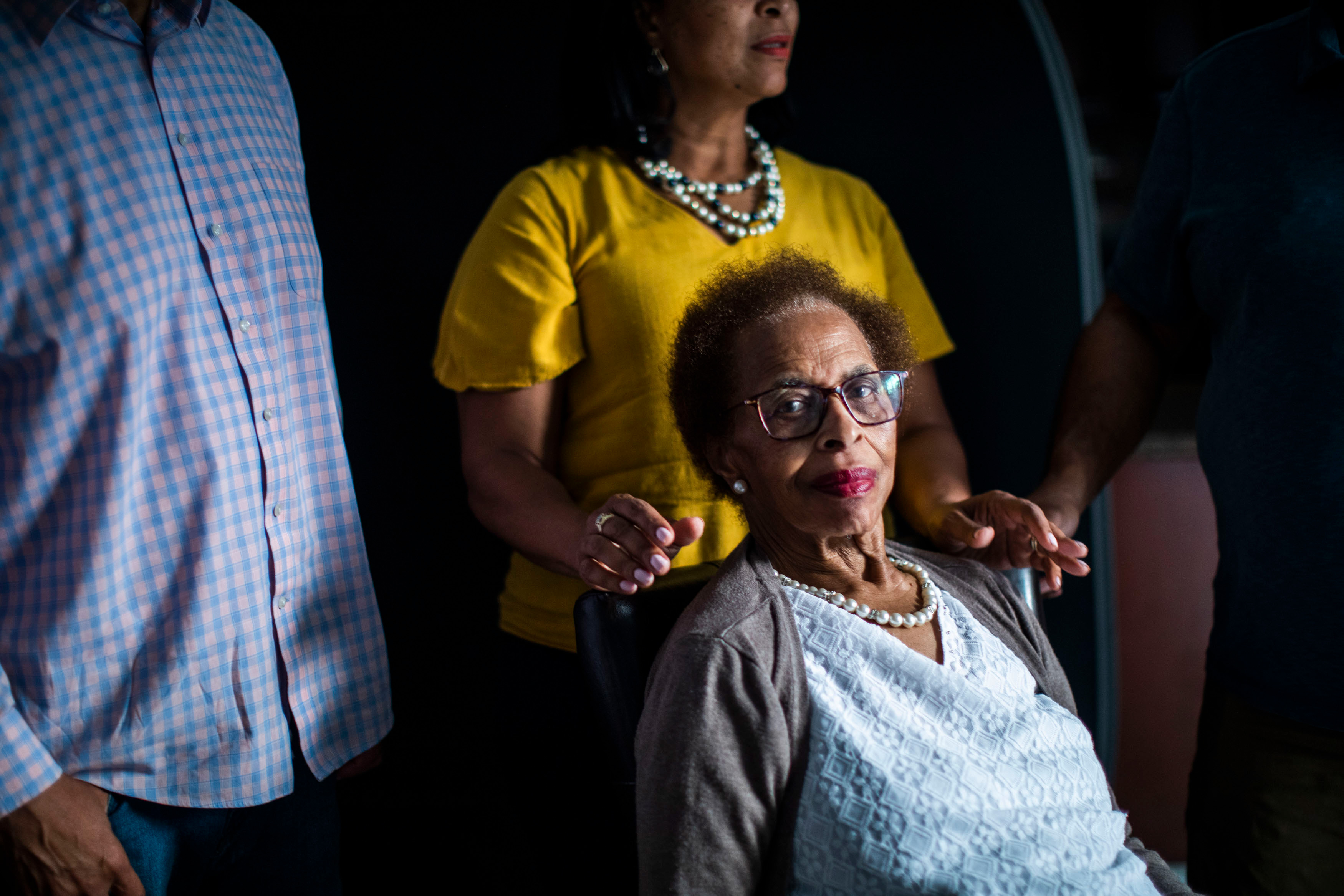 A photo of an elderly woman seated for a portrait with her adult daughter behind her.