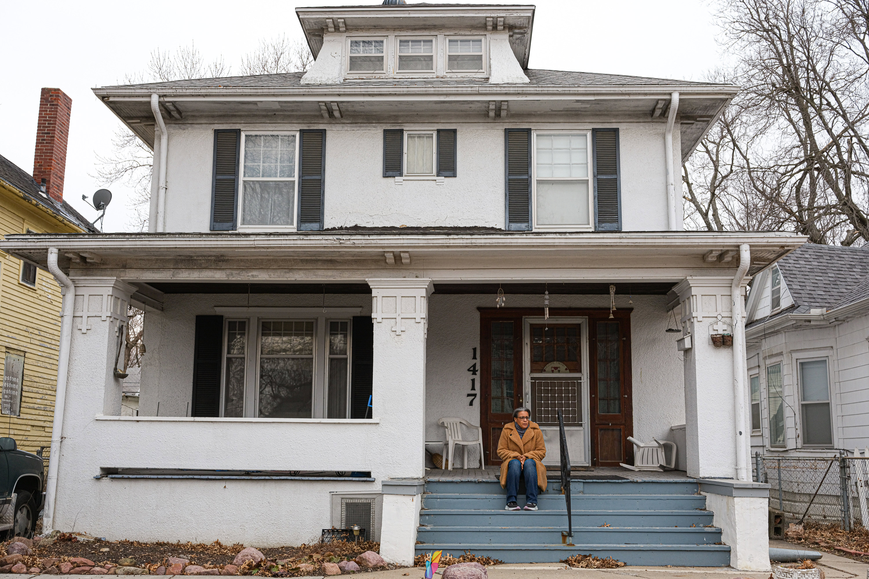 A photo of a woman sitting on steps of her front porch.