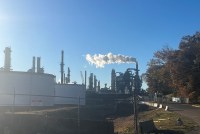 A smoke plume billows from an oil refinery