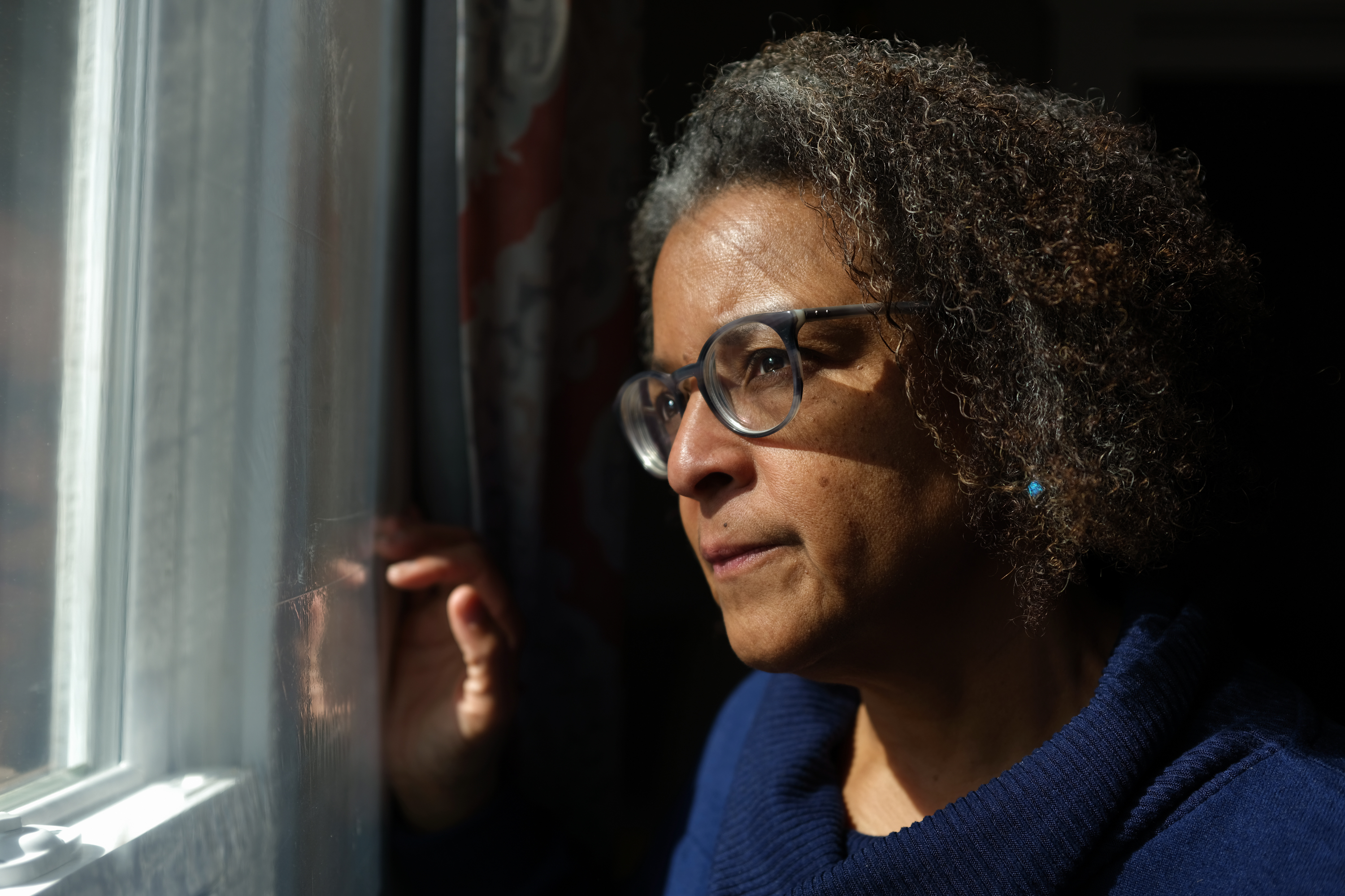 A photo of a woman looking out of a window.