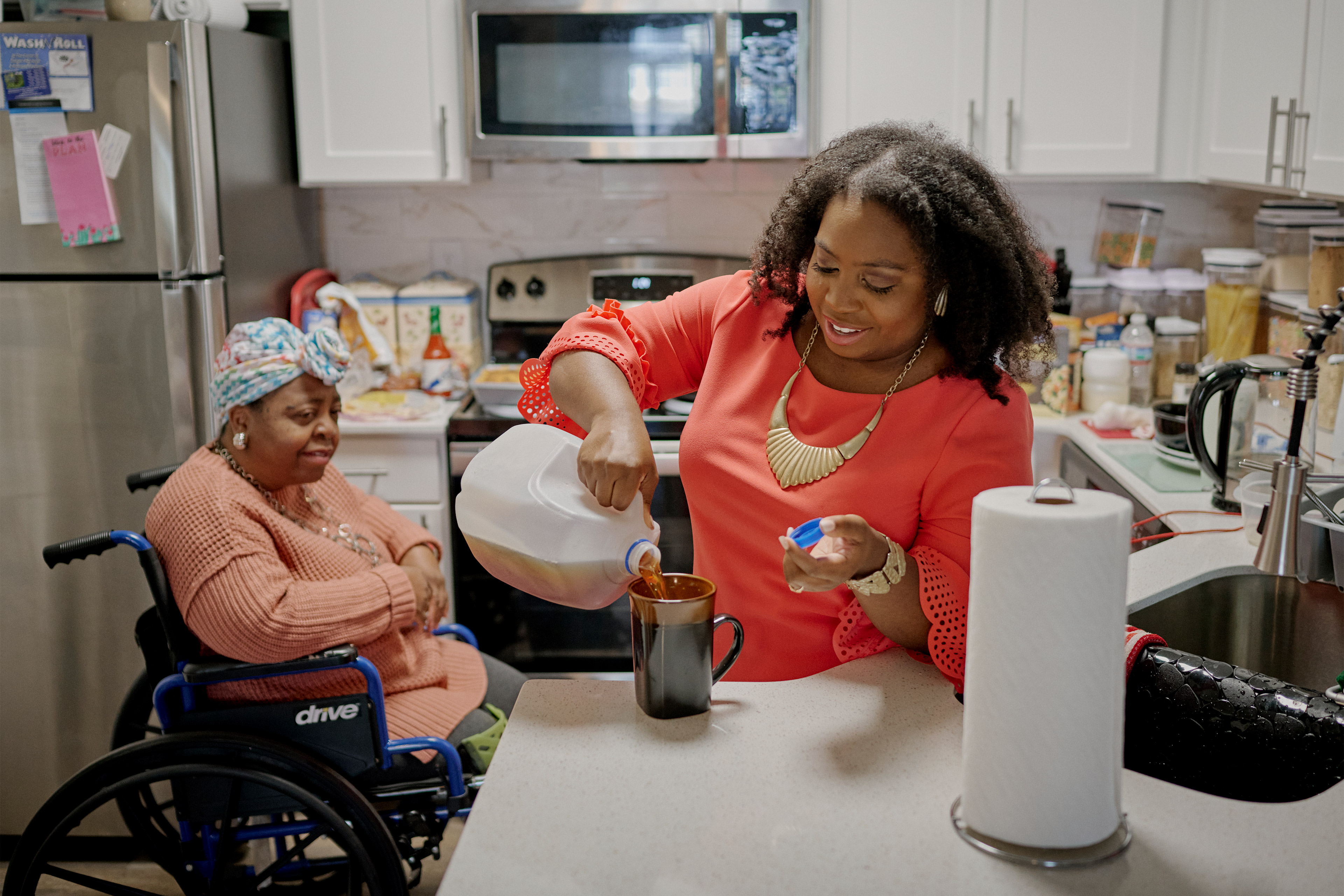 A photo of a woman pouring a cup of tea for her elderly mother.