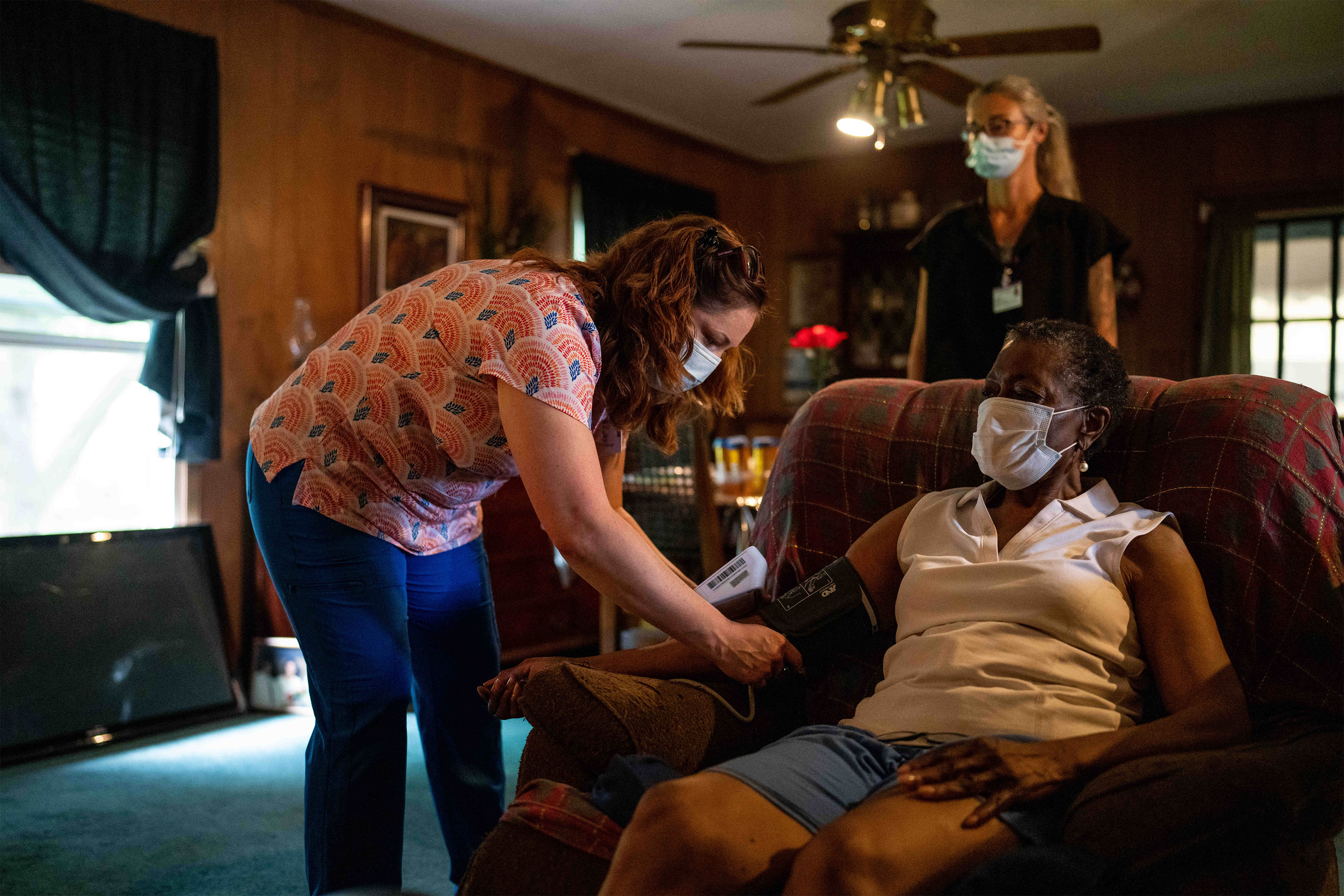 A photo of a caretaker taking an elderly woman's blood pressure at home.