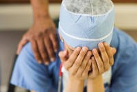 A health care worker is. sitting with their head in their hands.