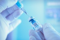 An up close photograph of a medical worker preparing measles, mumps, and rubella vial for vaccination.