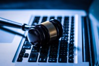 A photo of a judge's gavel resting on a laptop.