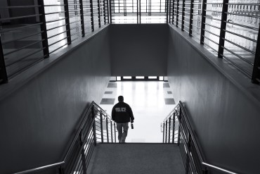 A photo a police officer walking down a set of stairs inside of a school.