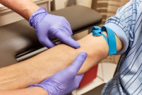 A health care technician preps the arm of a senior adult for a blood draw.