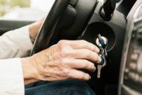 A photo of an older person's hand putting their car key in the ignition.