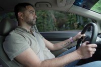 A photo of a Latino man driving in his car.