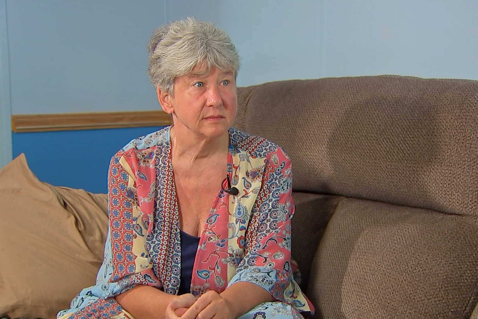 A photo of a woman sitting on a couch and facing to the right.