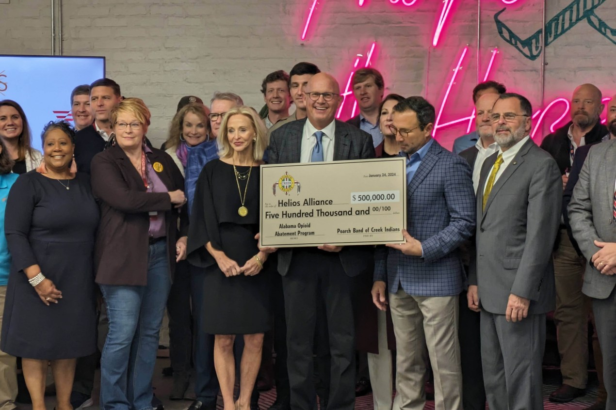 Stephen Loyd, center, stands in a crowd holding a foam-board check for $500,000.00 for the Helios Alliance.