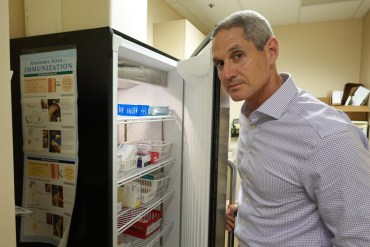 A photo of a doctor opening a refrigerator.